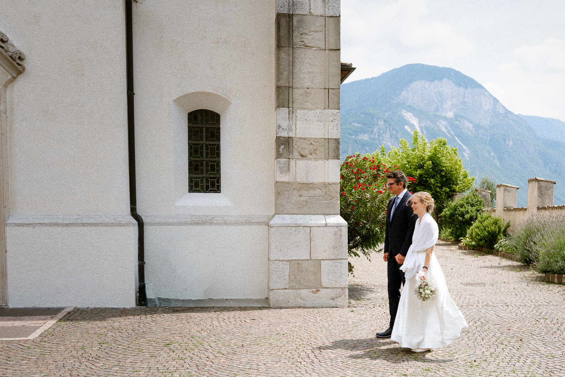 Brautpaar erreicht die Kirche kurz vor der Hochzeitszeremonie und wird von Familie und Freunden begrüßt. Brautpaar erreicht die Kirche vor Beginn der Hochzeitszeremonie Emotionaler Moment beim Eintreffen des Brautpaares an der Kirche Braut und Bräutigam kommen gemeinsam zur Kirche Ankunft des Brautpaares vor der kirchlichen Trauung Glückliches Brautpaar erreicht die Kirche am Hochzeitstag Brautpaar wird vor der Kirche von Gästen empfangen Romantischer Moment bei der Ankunft des Brautpaares an der Kirche Brautpaar kurz vor dem Einzug in die Kirche Emotionale Hochzeitsmomente vor der Kirche in Wien Brautpaar vor der Kirche auf dem Weg zur Trauung