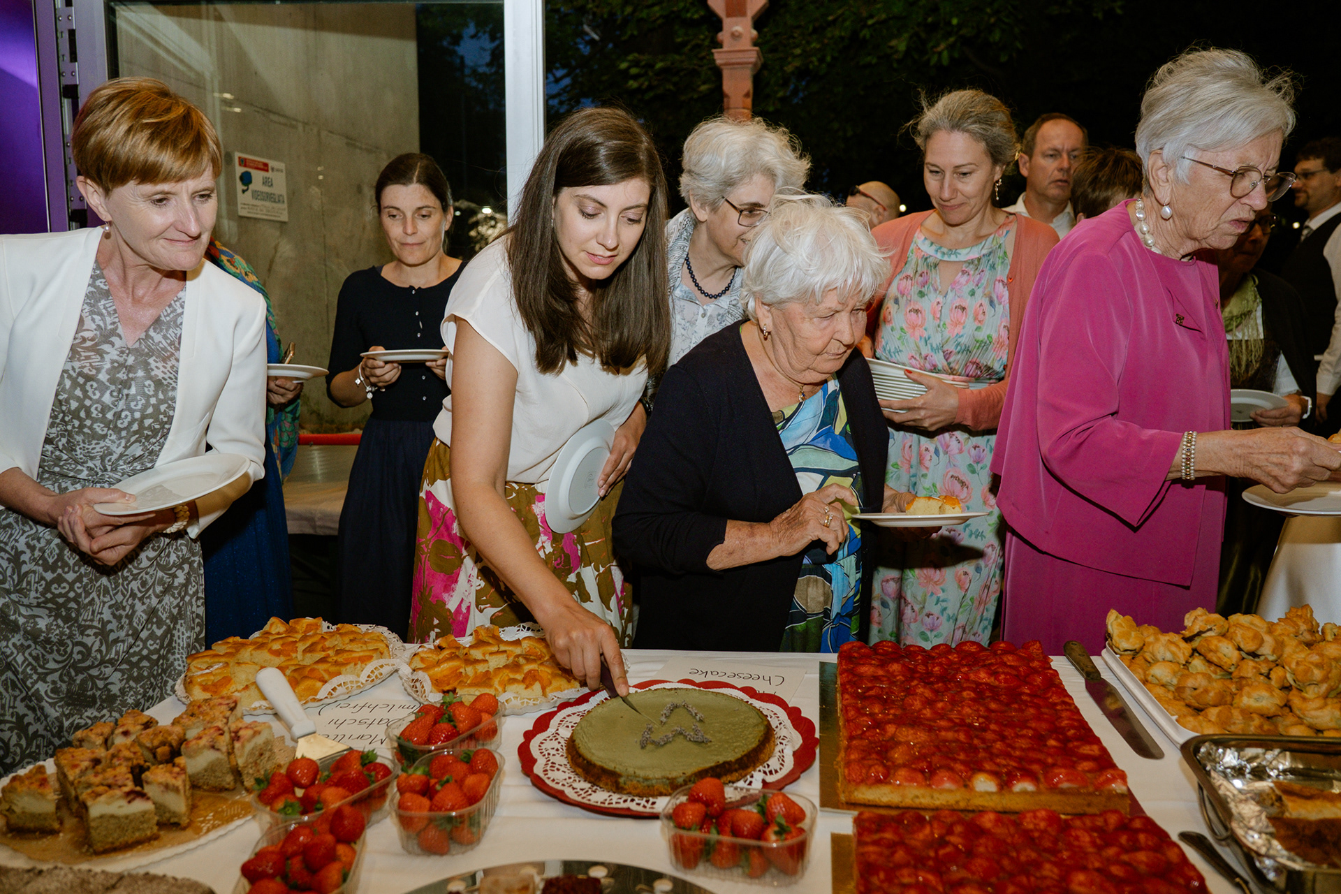 Kuchenbuffet auf einer Hochzeit mit Gästen in Aktion Fröhliche Gäste greifen beim Hochzeits-Kuchenbuffet zu Hochzeitsfeier: Gäste holen sich Kuchen vom Buffet Kuchenbuffet mit Gästen während der Hochzeitsfeier Süßes Hochzeitsbuffet: Gäste bedienen sich am Kuchen Moment am Kuchenbuffet während einer Hochzeit mit Gästen Hochzeitsgäste genießen Kuchen vom Buffet Lebendiges Kuchenbuffet auf der Hochzeitsfeier