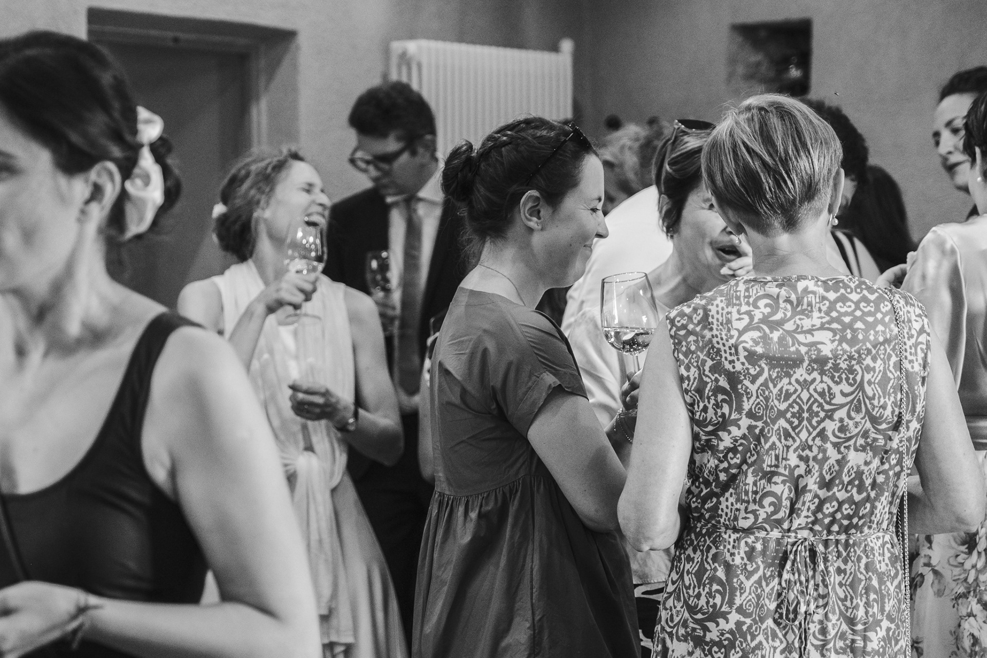 Fröhliche Braut lacht glücklich im Kreis ihrer Hochzeitsgesellschaft während der Feier am Hochzeitstag