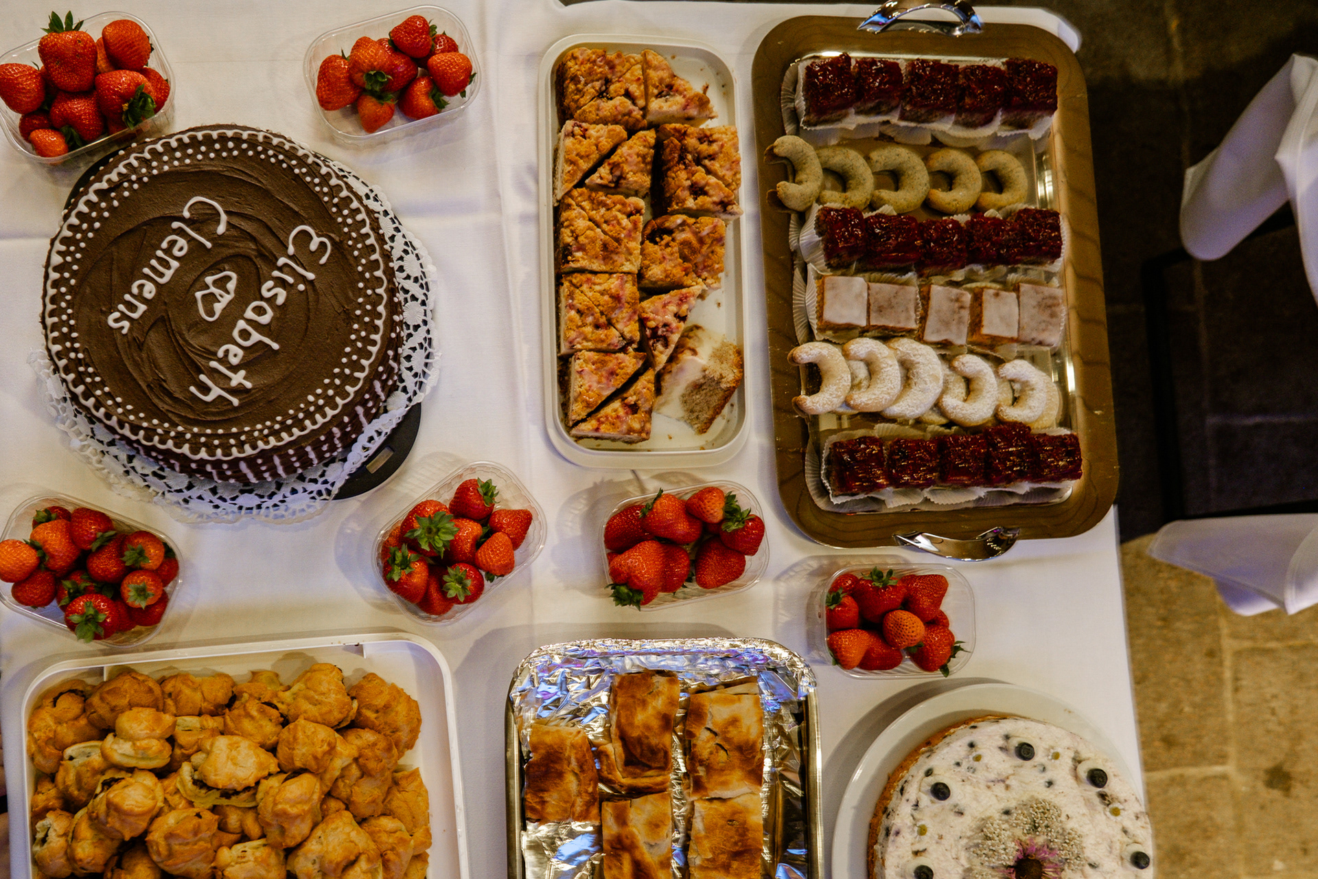 Gäste bedienen sich am Kuchenbuffet während der Hochzeitsfeier und genießen verschiedene Torten und Süßspeisen
